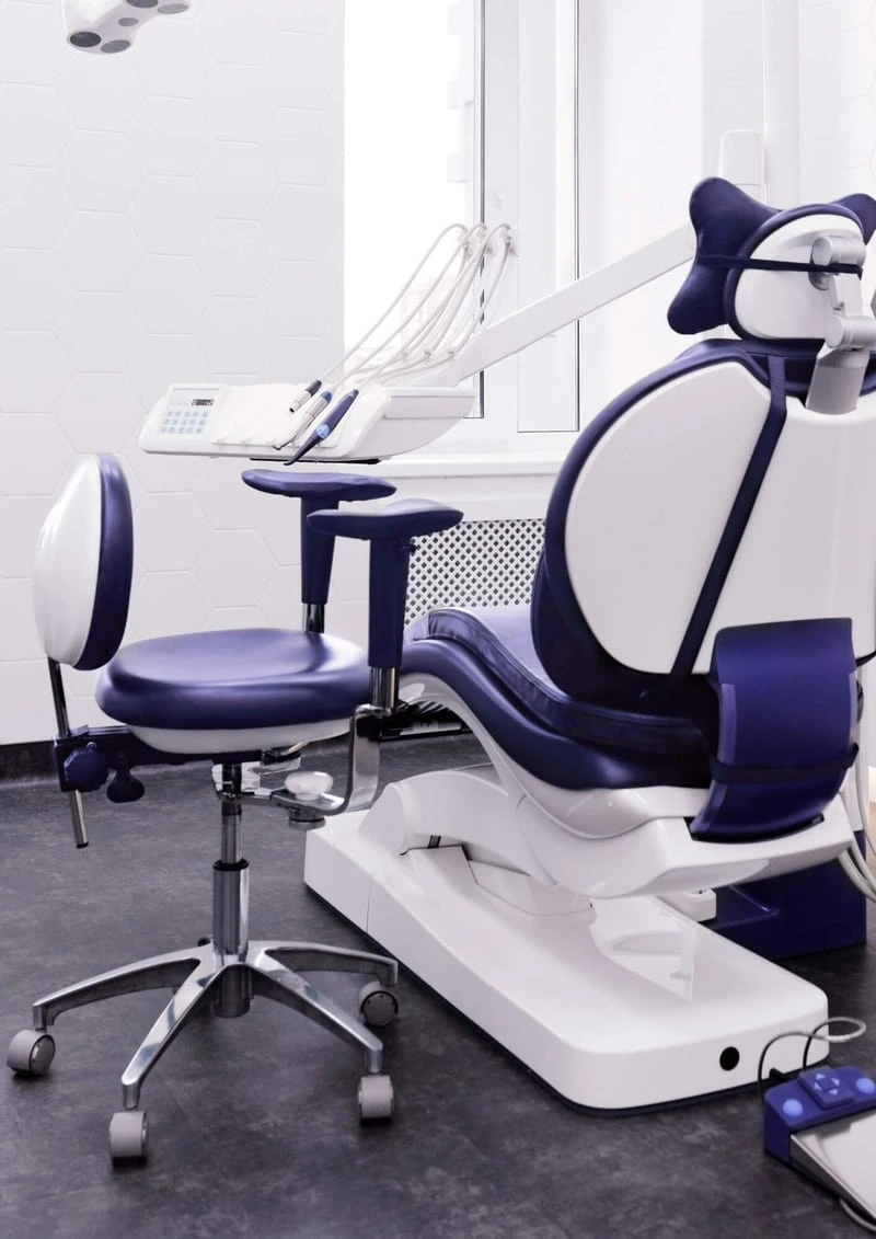 Consultório odontológico equipado com cadeira de atendimento moderna nas cores azul e branca, com acabamento ergonômico e instrumentos de alta tecnologia ao fundo. O ambiente limpo, iluminado e com design sofisticado transmite profissionalismo, conforto e excelência nos cuidados odontológicos — ideal para procedimentos como implantes, ortodontia e estética dental.